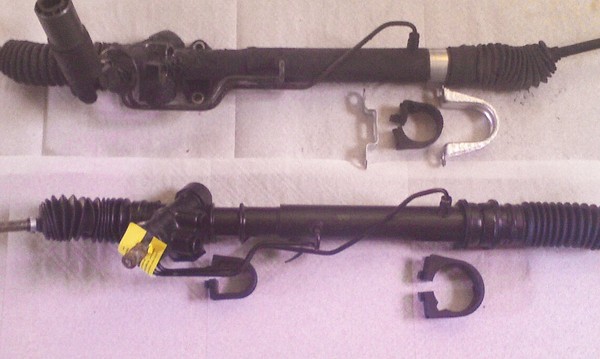 The old rack (top) mounts to the front suspension crossmember on the driver's side using feet cast into the housing.  The new rack (bottom) uses a second rubber isolator, like the one on the passenger's side only smaller.